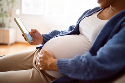 pregnant woman looking at adoption profiles on her phone